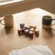 Küchentisch mit zwei Kaffeetassen und bunten Kinderbauklötzen in warmem Morgenlicht